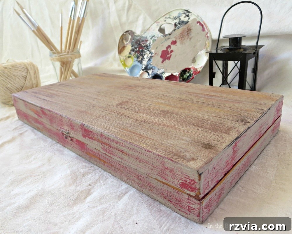 An angled view of the beautifully painted box, showing its multi-faceted design and the successful transformation from a laminate surface to a textured, aged wood look. The red accents are subtly integrated into the overall design.