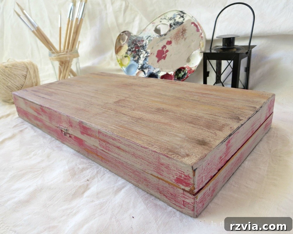 The final completed backgammon laminate box, expertly painted with chalk paint to achieve an aged wood appearance. The box is displayed prominently, showcasing its rustic texture, distressed finish, and the subtle integration of red accents. This 'after' image highlights the remarkable transformation.