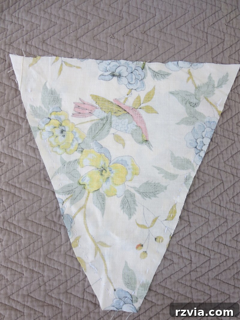 Detailed shot of fabric triangles being sewn together, showing the seams up to an inch from the top edge, a key step in creating a beautiful DIY fabric banner. Perfect for crafting personalized home decor.