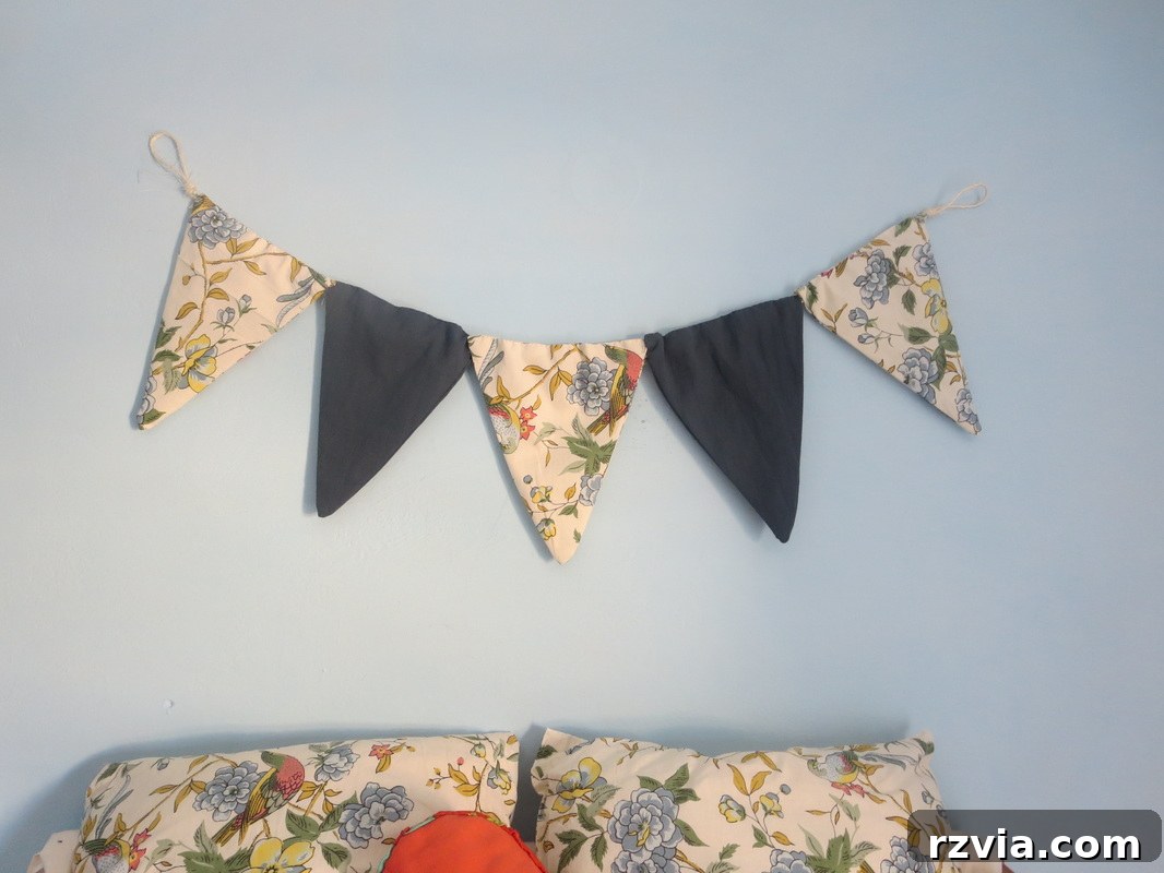 The newly hung DIY fabric banner proudly displayed above matching throw pillows, creating a cohesive and personalized look for the blue room. A perfect example of repurposing fabric for stylish home decor.