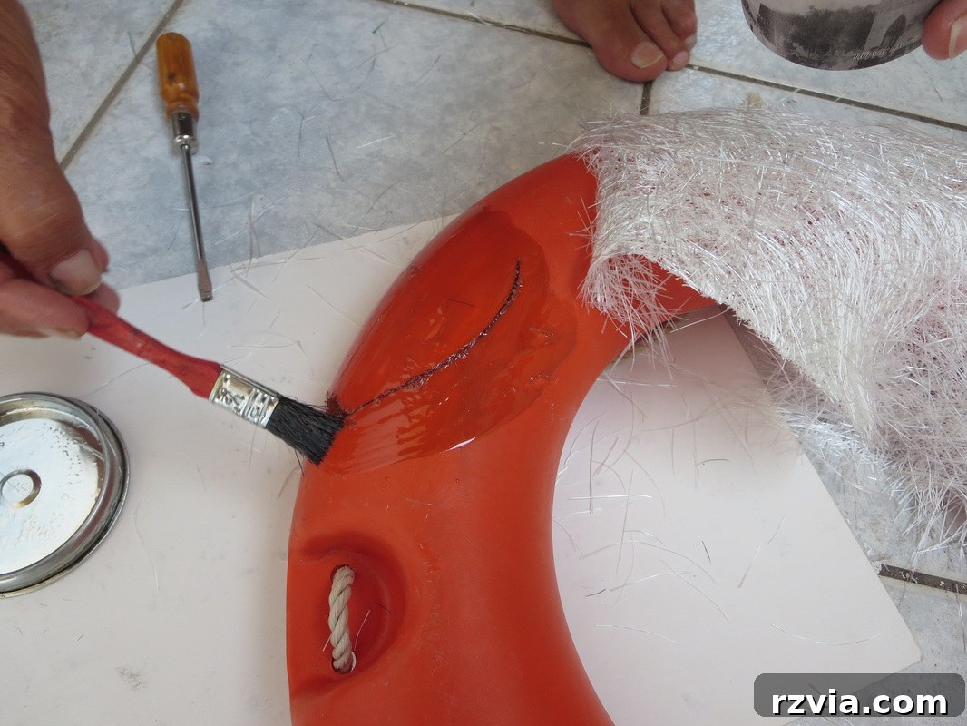 Applying polyester resin to the damaged area of the lifesaver, beginning the repair.