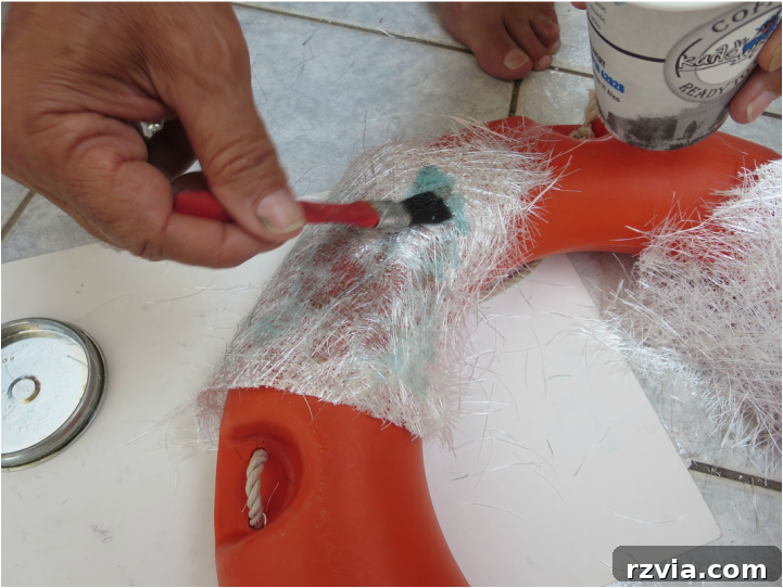 Soaking fiberglass mat with polyester resin for a strong and durable repair.