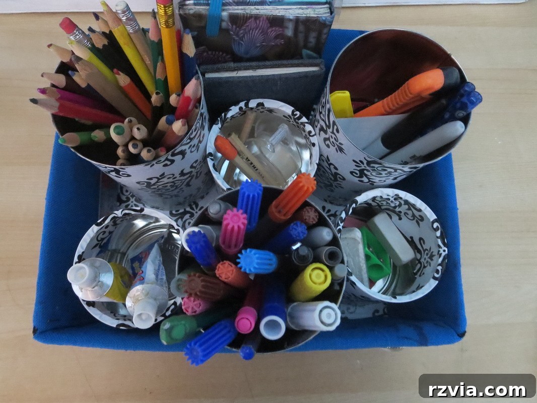 Newly covered tin cans with elegant black and white contact paper, prepared for their role as desk organizers.