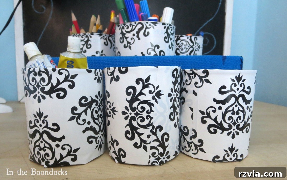 Close-up of the stylish black and white contact paper covered tin cans holding colorful pens and markers, demonstrating their new functionality.