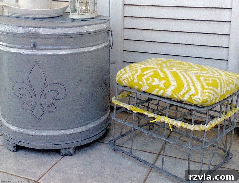 The newly finished repurposed milk crate stool, complete with its bright cushion, placed artfully beside a coordinating revamped barrel, adding style to an outdoor space. Sustainable home furnishings.