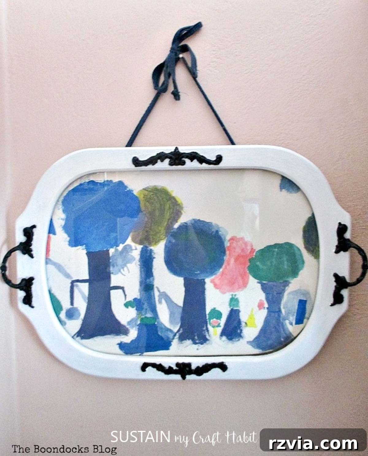 Reimagining a Vintage Serving Tray 8 A child's artwork mounted behind the glass of an old wood serving tray painted white and hanging on the wall.