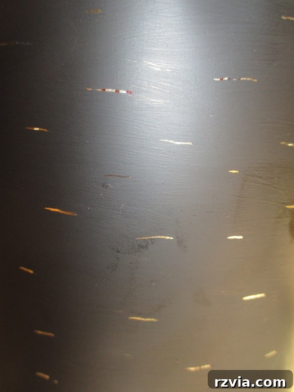 Close-up detail of the distressed honey tin, showing the scratches made to reveal the original gold underneath the black paint. This DIY technique creates a rustic, aged finish for the upcycled kitchen utensil holder.