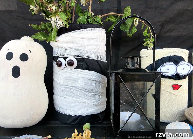 Repurposed tin cans creatively decorated as mummies for a fun Halloween vignette.