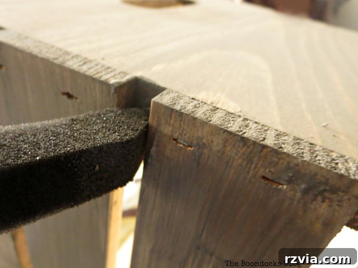 Detailed image showing the application of barnwood stain in the tight crevices of the wooden crate with a foam brush.