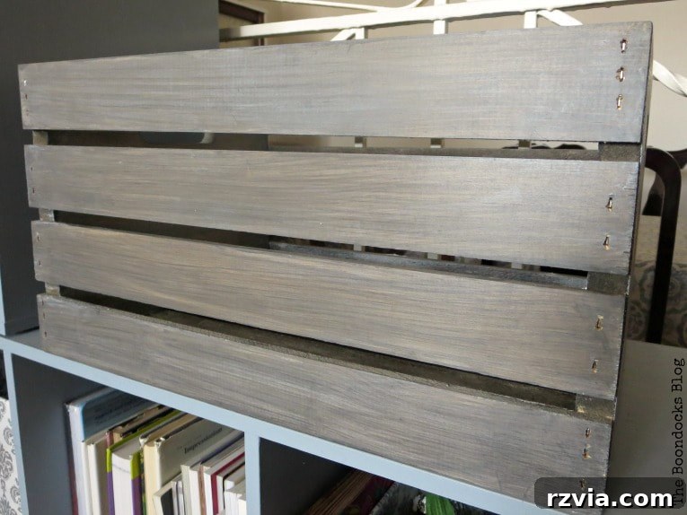 Close-up of the wooden crate being buffed with a lint-free rag after applying white decorative wax, showcasing a smooth, sealed finish.