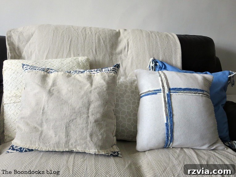 From Discarded to Desired: Upcycling Your Clothes with Style 14 Elegant white throw pillows displayed on a couch, showcasing designs made from repurposed sweaters and lace dresses.