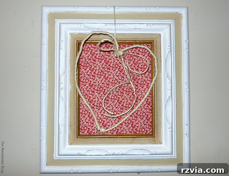 From Discarded to Desired: Upcycling Your Clothes with Style 7 A decorative picture frame featuring a wire heart against a backdrop of repurposed calico skirt fabric, creating a rustic art piece.