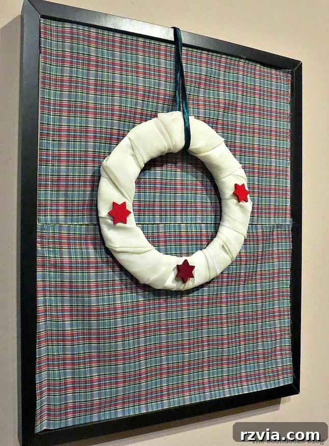 From Discarded to Desired: Upcycling Your Clothes with Style 8 A rustic Christmas wreath elegantly displayed within a repurposed picture frame, with a fabric backdrop made from old boxer shorts.