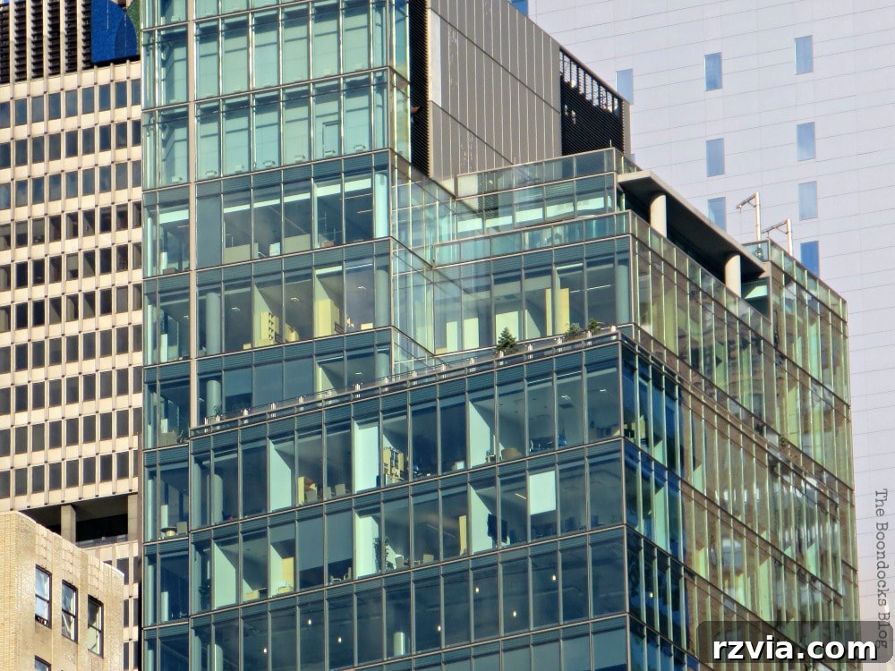 A modern glass skyscraper standing tall in Midtown Manhattan, New York, reflecting the surrounding urban landscape and sky.
