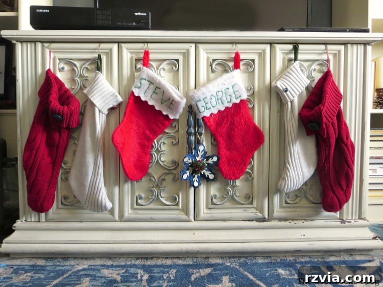 Repurpose Old Sweaters into Christmas Stockings 2 Cozy red sweater Christmas stockings hanging on a white decorative cabinet, ready for the holidays.