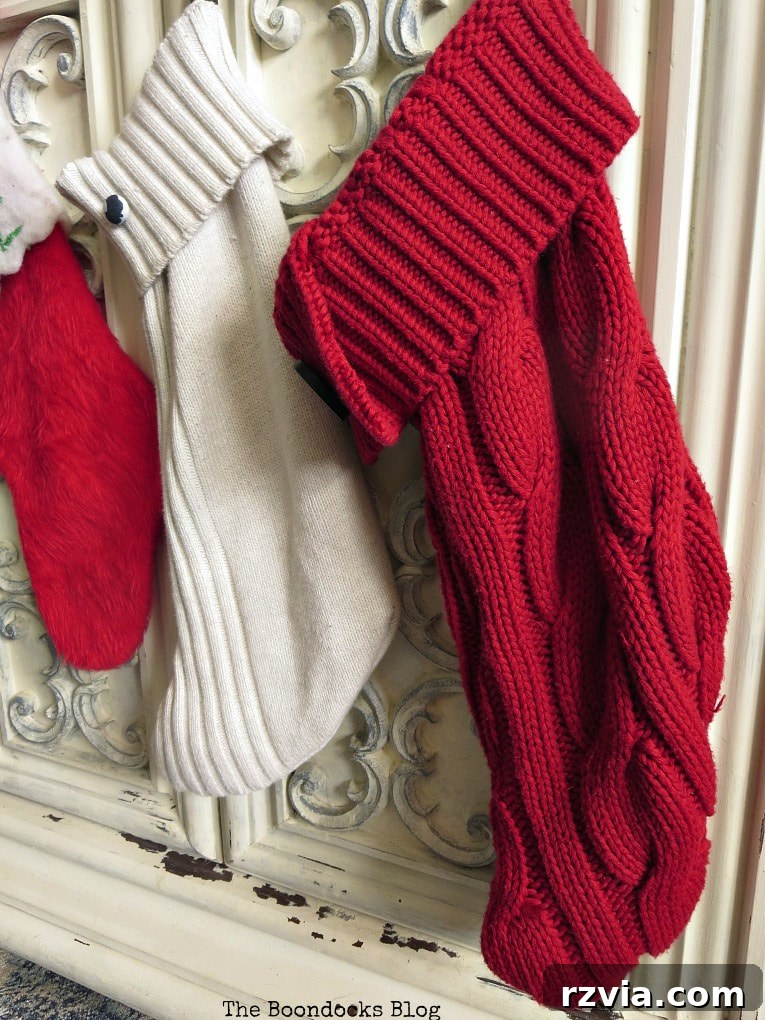Repurpose Old Sweaters into Christmas Stockings 12 A collection of handmade sweater stockings, showcasing various colors and button embellishments, hanging on a vintage TV cabinet.
