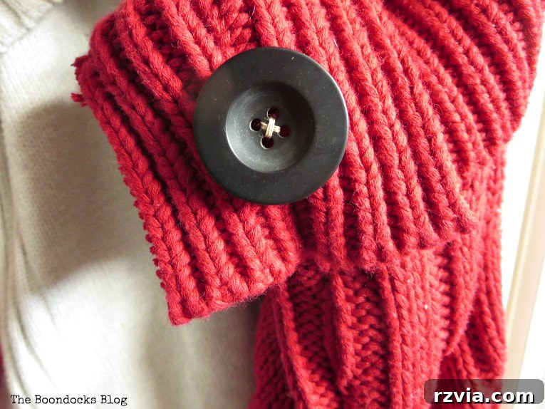 Repurpose Old Sweaters into Christmas Stockings 8 Close-up of a red sweater Christmas stocking adorned with a black button and festive ribbon.