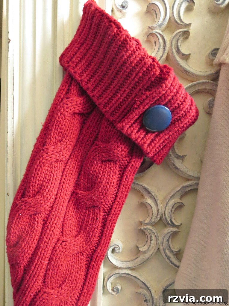 Repurpose Old Sweaters into Christmas Stockings 9 A second red sweater Christmas stocking with a blue button for identification, hanging on a cabinet.
