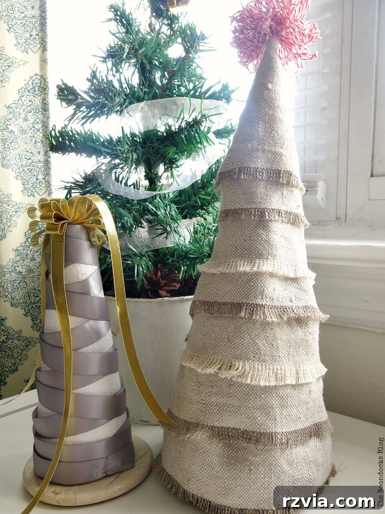 Craft a Charming Fabric Mini Tree from Dollar Store Finds 14 A charming collection of mini Christmas trees: one exquisitely crafted with fabric scraps, showcasing its boho aesthetic, beside another tree elegantly wrapped in grey and gold ribbon shaped into a Christmas tree. Both are positioned in front of a miniature potted evergreen tree, creating a harmonious and festive display.