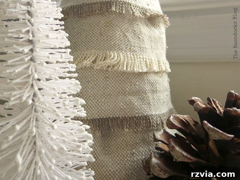 Craft a Charming Fabric Mini Tree from Dollar Store Finds 3 A close-up view of a trio of festive elements: a pristine white miniature Christmas tree, the newly crafted fabric scrap Christmas tree showcasing its intricate details, and a natural pinecone, all contributing to a charming holiday vignette.