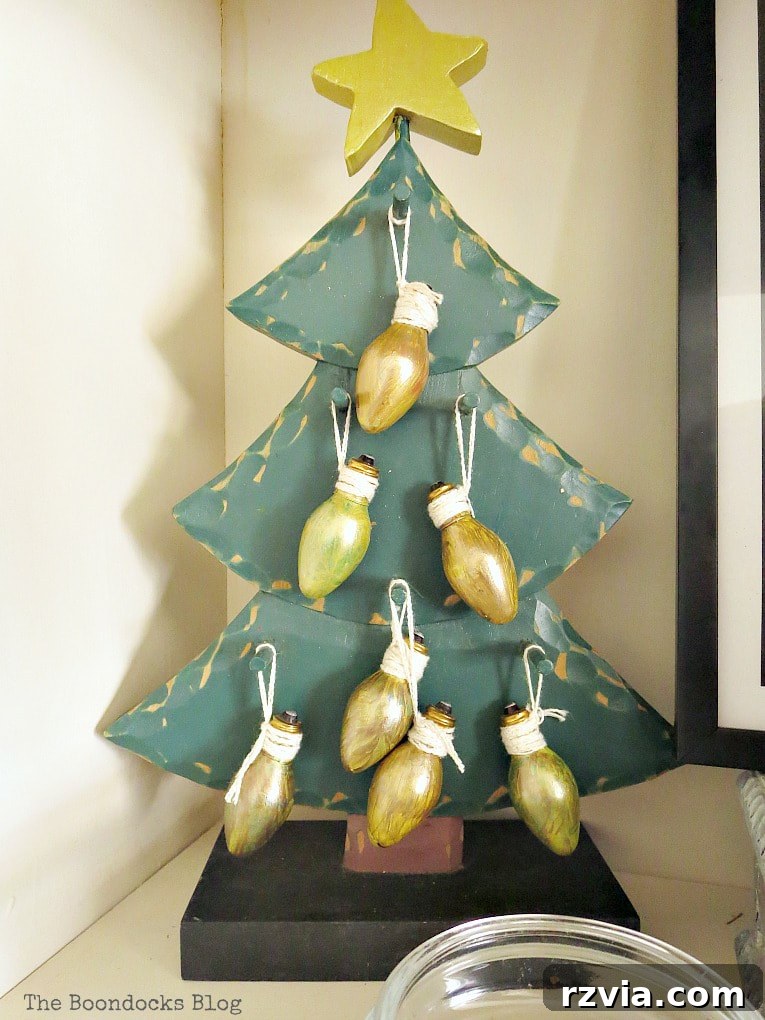 Repurpose Old Decor for Stunning Christmas Vignettes 12 A green wooden Christmas tree adorned with light bulbs painted gold, showcasing a creative DIY approach to upcycling and personalizing holiday decor.
