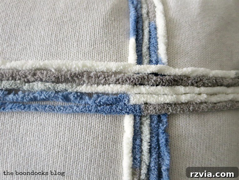 Upcycle Your Fabric Scraps: 5 Easy Pillow Projects 11 Close-up detail of the yarn embellishment creating a ribbon effect on the upcycled sweater pillow.