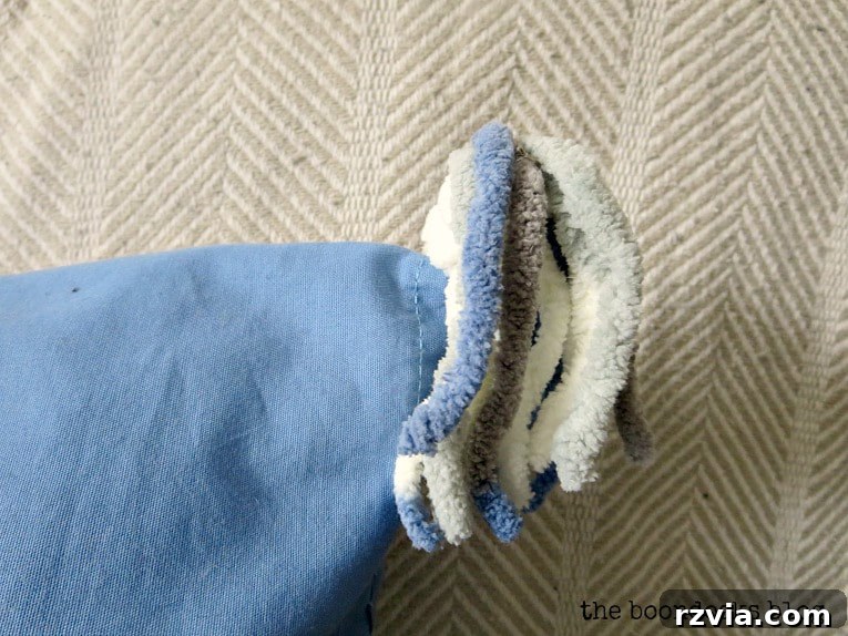 Upcycle Your Fabric Scraps: 5 Easy Pillow Projects 13 Close-up view of the handmade yarn tassels adding a whimsical touch to the blue upcycled pillow.