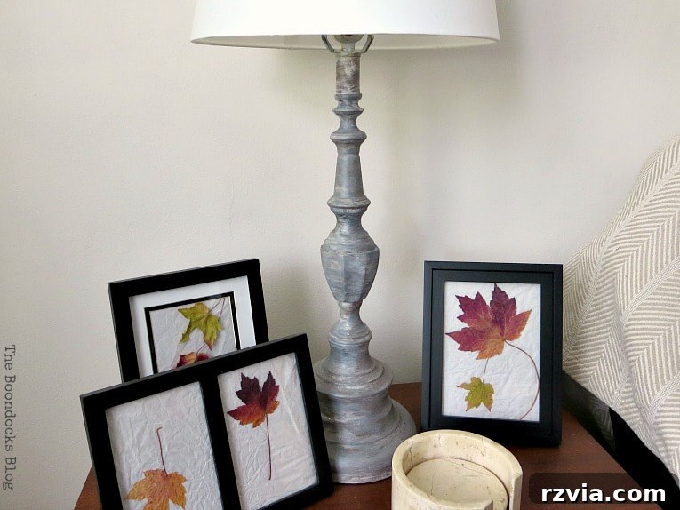Give Your Lamp Base a High-End Stone Look 12 The newly painted stone-look lamp base positioned on a wooden table, flanked by framed pictures featuring leaves. The lamp beautifully complements the natural tones and textures of the surrounding decor, enhancing the room's overall aesthetic.