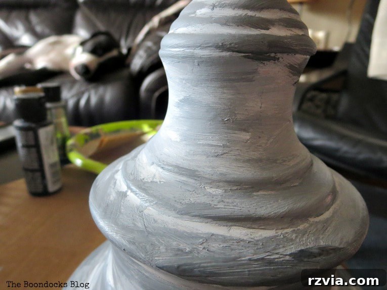 Give Your Lamp Base a High-End Stone Look 7 Applying dry brushing technique to the lamp base. The brush holds very little paint, creating a subtle, textured layer that highlights the ridges and forms of the lamp, enhancing the stone effect. This process adds fine detail and depth to the finish.