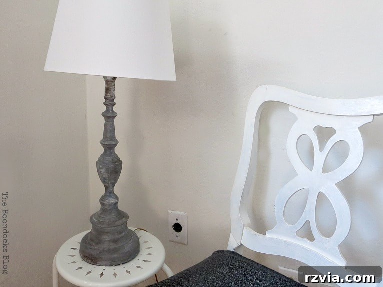 Give Your Lamp Base a High-End Stone Look 10 The finished painted lamp, now resembling stone, placed on a white table beside a white chair. The room is brightly lit, highlighting the lamp's new texture and adding a sophisticated touch to the space.