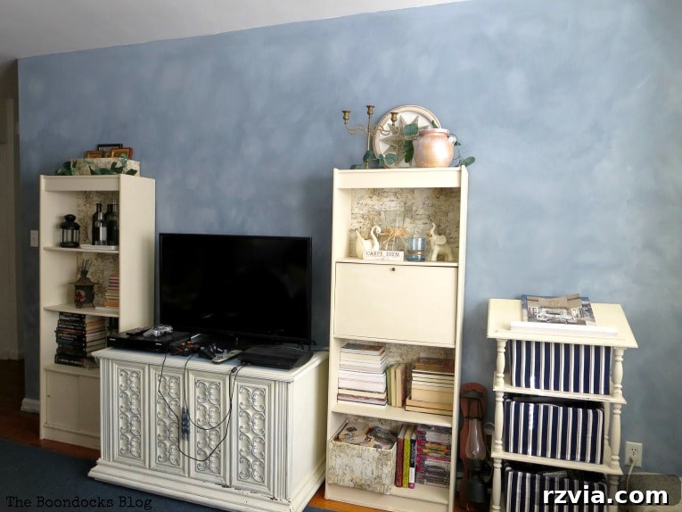 Create Your Own Dreamy Cloud Accent Wall 21 The finished living room, featuring a TV, bookcases, and other furniture elegantly arranged in front of the newly painted cloudy accent wall.