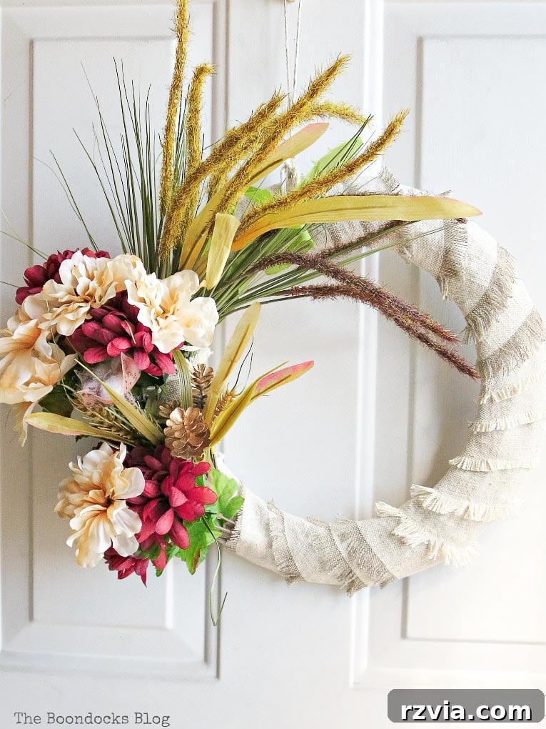 A beautifully finished DIY dollar store fall wreath, rich in autumn colors and natural textures, ready to adorn a front door.