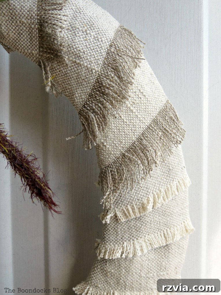 Detailed view of the fabric-wrapped wreath, focusing on the elegantly frayed edges that add a unique, rustic texture to the design.