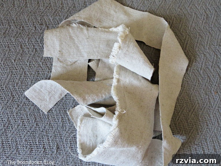 Four strips of light-colored fabric laid out, two cut vertically and two horizontally, ready to be joined for the fall wreath.