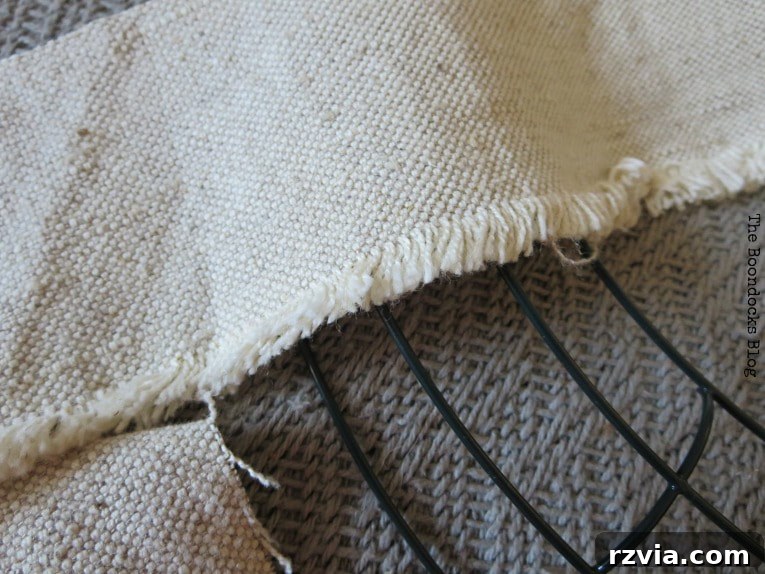 Close-up of the frayed edges of the fabric strips, showing the distinct white and taupe colors created by cutting along different fabric grains.