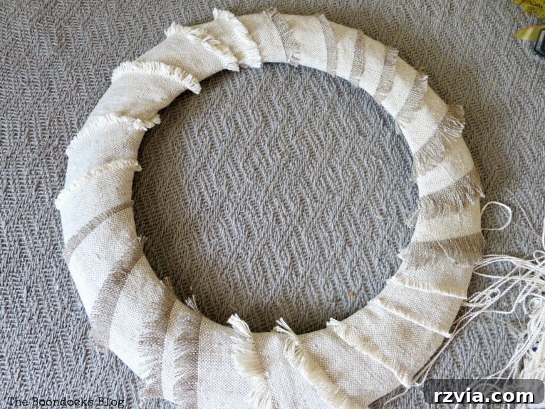 The completed fabric-wrapped wire form, showcasing the distinct frayed edges and varied textures on the base of the DIY fall wreath.