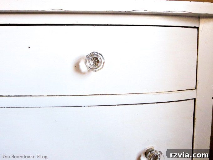 Jewel Your Furniture: Crystal Knobs for an Instant Upgrade 4 Close-up of new crystal glass knobs on a vintage distressed white dresser, adding a touch of sparkle.