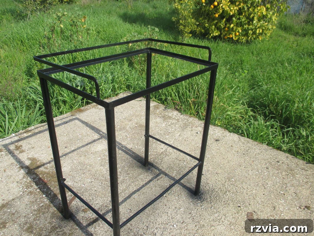 The metal table frame after being spray-painted black, showing a smooth and refreshed finish.
