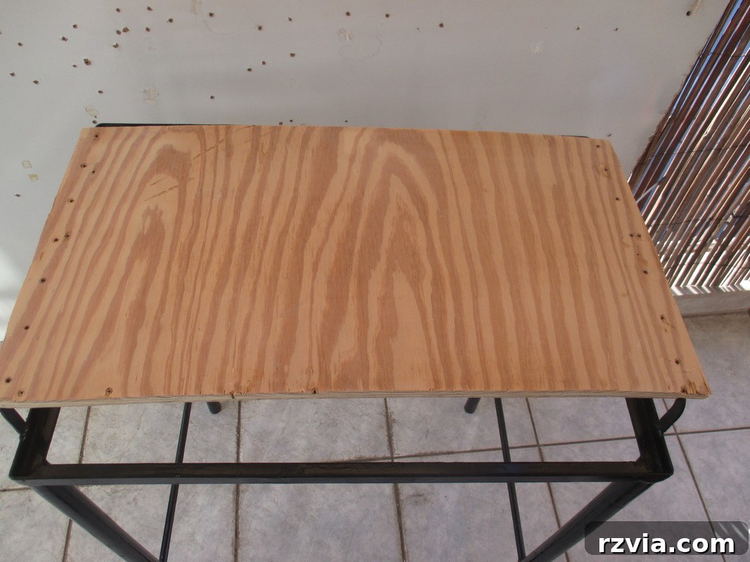 A piece of plywood cut to fit as a new bottom shelf for the refurbished metal table.