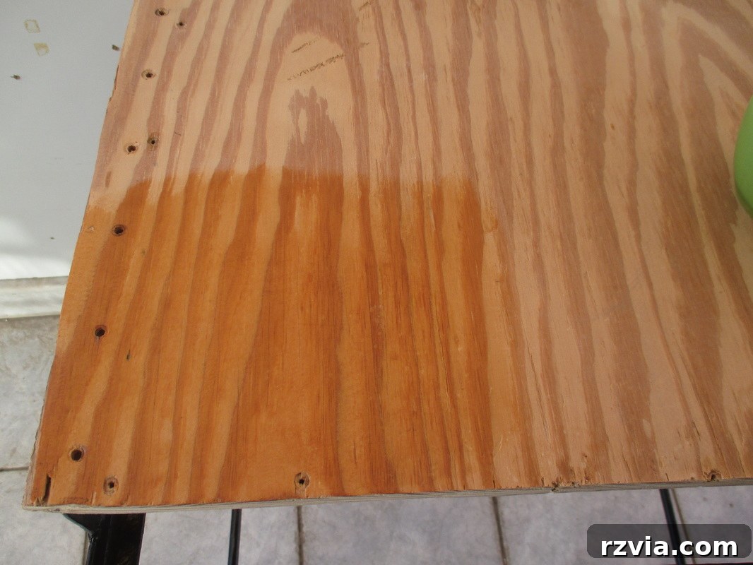 Wiping the plywood shelf with an oil and vinegar solution to clean and add luster.