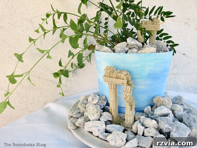 Seaside Style from Salvaged Treasures 3 A decorative planter with an aged, beach-inspired look, surrounded by pebbles and small 'ruins' for a unique coastal display.