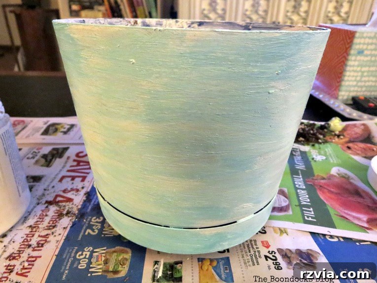 Seaside Style from Salvaged Treasures 10 Applying a mixed blue acrylic craft paint over the white chalk paint base to create a textured, Mediterranean-inspired finish on the planter.
