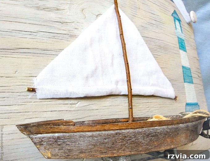 Coastal Creations from Repurposed Finds 17 Full view of the charming wooden boat with its fabric sail, integrated into the coastal wall art