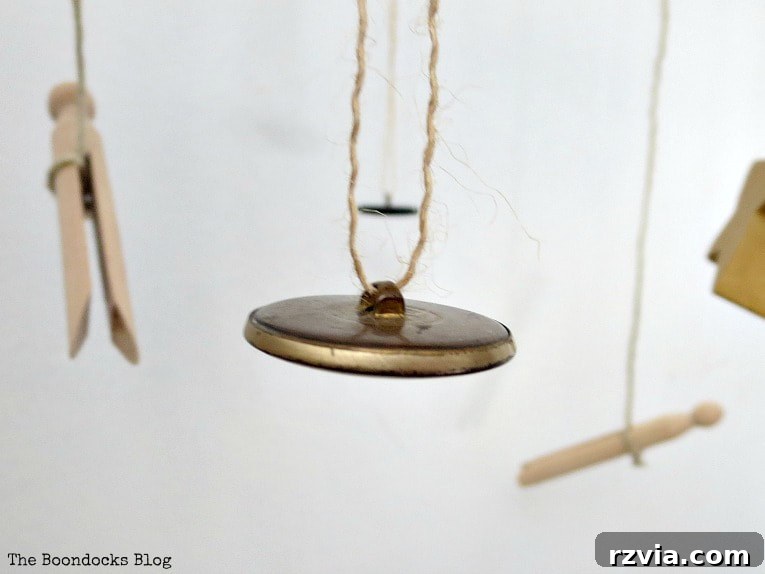 Beyond the Closet: Crafting Unique Mobiles from Wire Hangers 13 Close up of gold button hanging with twine and wooden pegs hanging with twine.