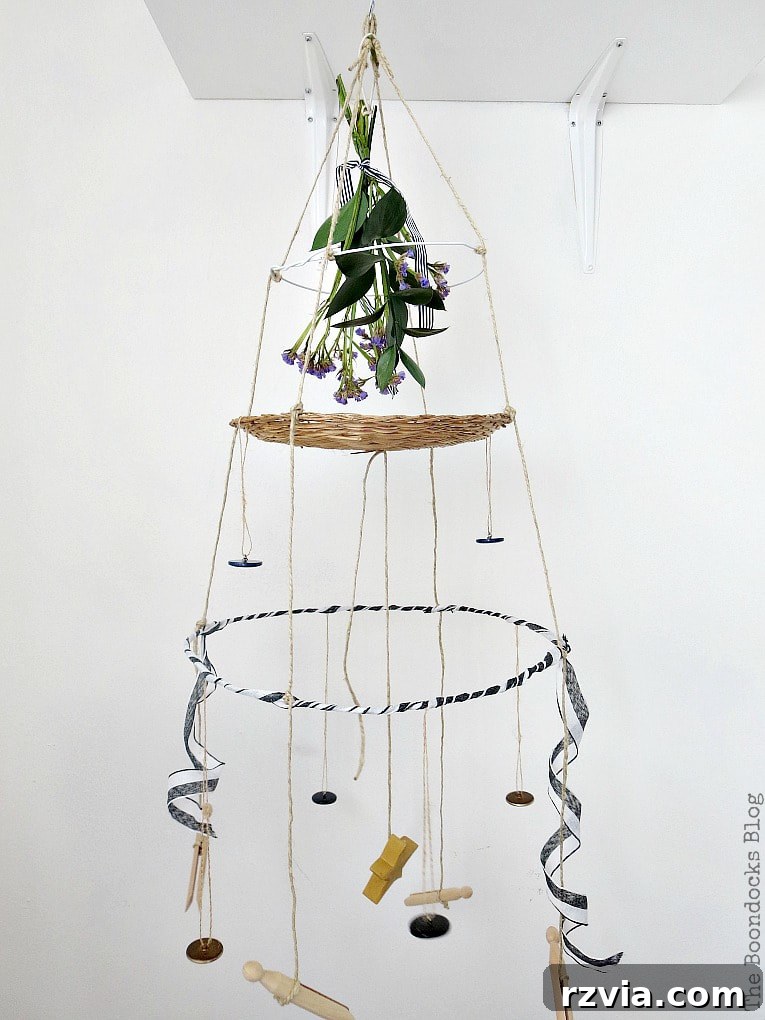 Beyond the Closet: Crafting Unique Mobiles from Wire Hangers 18 Completed mobile hanger with three tiers made with wire hangers, a wicker charger and twine, embellished with buttons, ribbon and a bouquet.