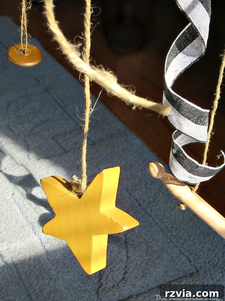 Beyond the Closet: Crafting Unique Mobiles from Wire Hangers 21 Close up of hanging wooden star, twine, buttons, wooden peg and ribbon.