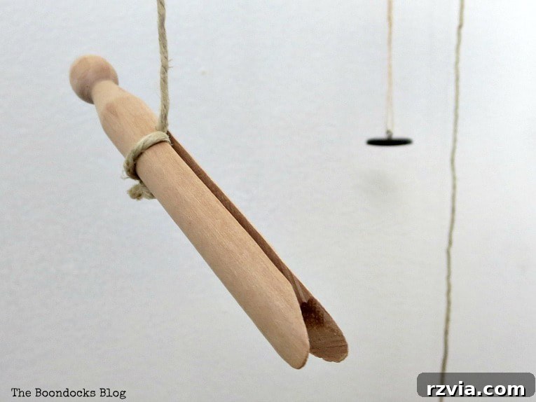 Beyond the Closet: Crafting Unique Mobiles from Wire Hangers 9 Attaching various objects on the bottom with twine, including a wooden clothes pin