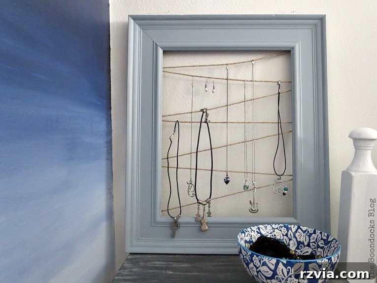 The completed DIY frame jewelry organizer with various necklaces and earrings neatly displayed on the twine. A perfect blend of style and function for decluttering.