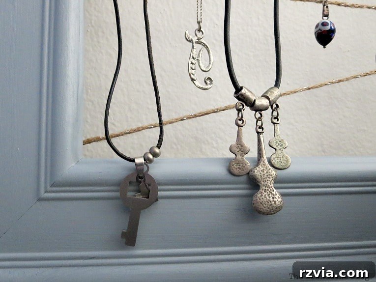 Another detailed shot of the organized jewelry on the repurposed frame, showcasing how well necklaces and earrings are separated and displayed on the twine.