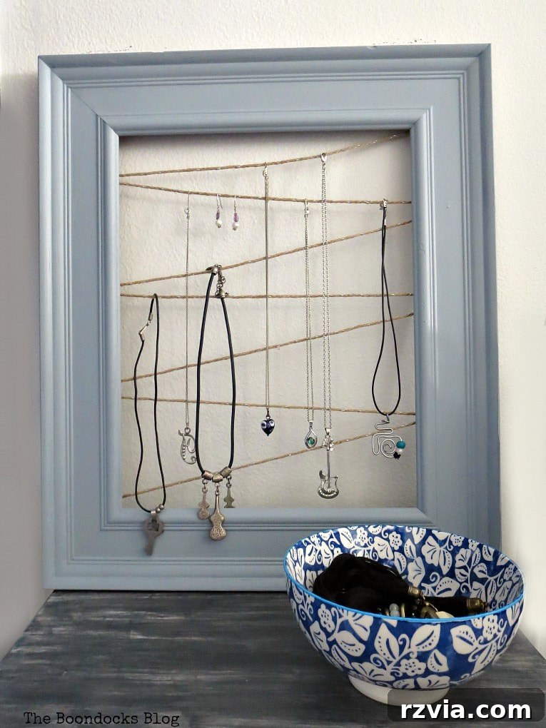 The repurposed frame jewelry organizer displayed beautifully, filled with various accessories. It's a perfect DIY storage solution and decorative piece.